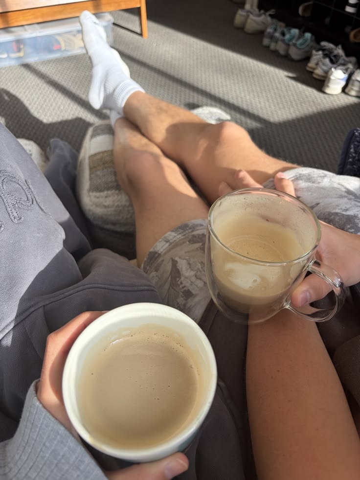 Two people with lattes on a sunlit couch